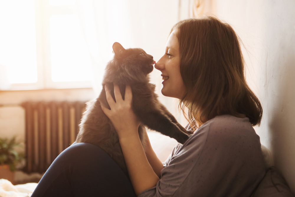 Young woman playing with her cat at home, celebrating the human-pet bond in Houston